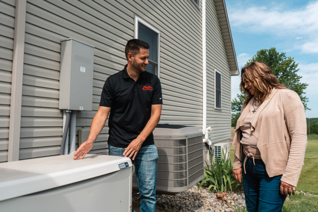 Flow-Tech technician discussing outdoor heating and cooling equipment with a homeowner
